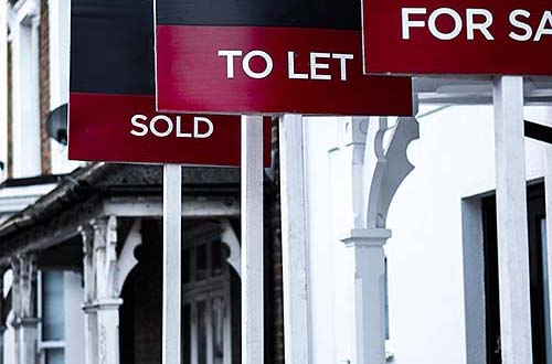 Estate agent 'for sale', 'to let' and 'sold' signage boards of street of terraced houses